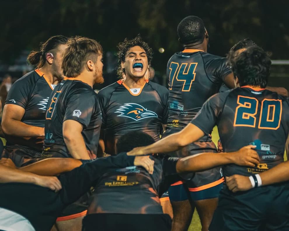 UTSA university rugby players fired up in a team huddle under floodlights