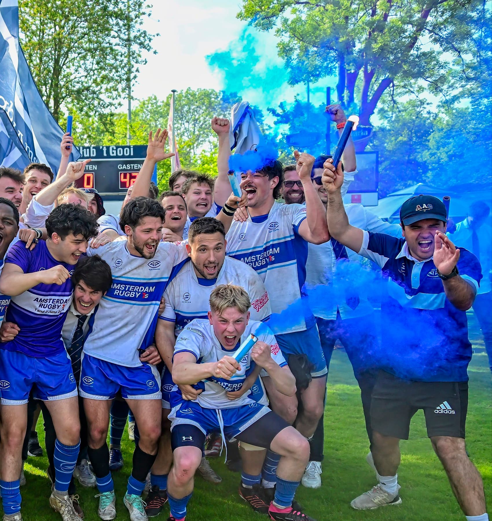 AAC rugby team celebrating a league title win with blue smoke flares on the pitch